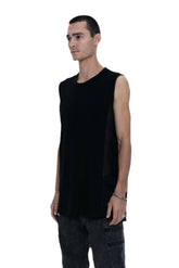 Person wearing a black sleeveless shirt, dark pants, and black boots on a white background
